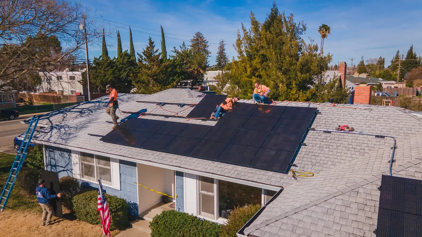 Two Westhaven installers carry a solar panel across a lawn toward the house.