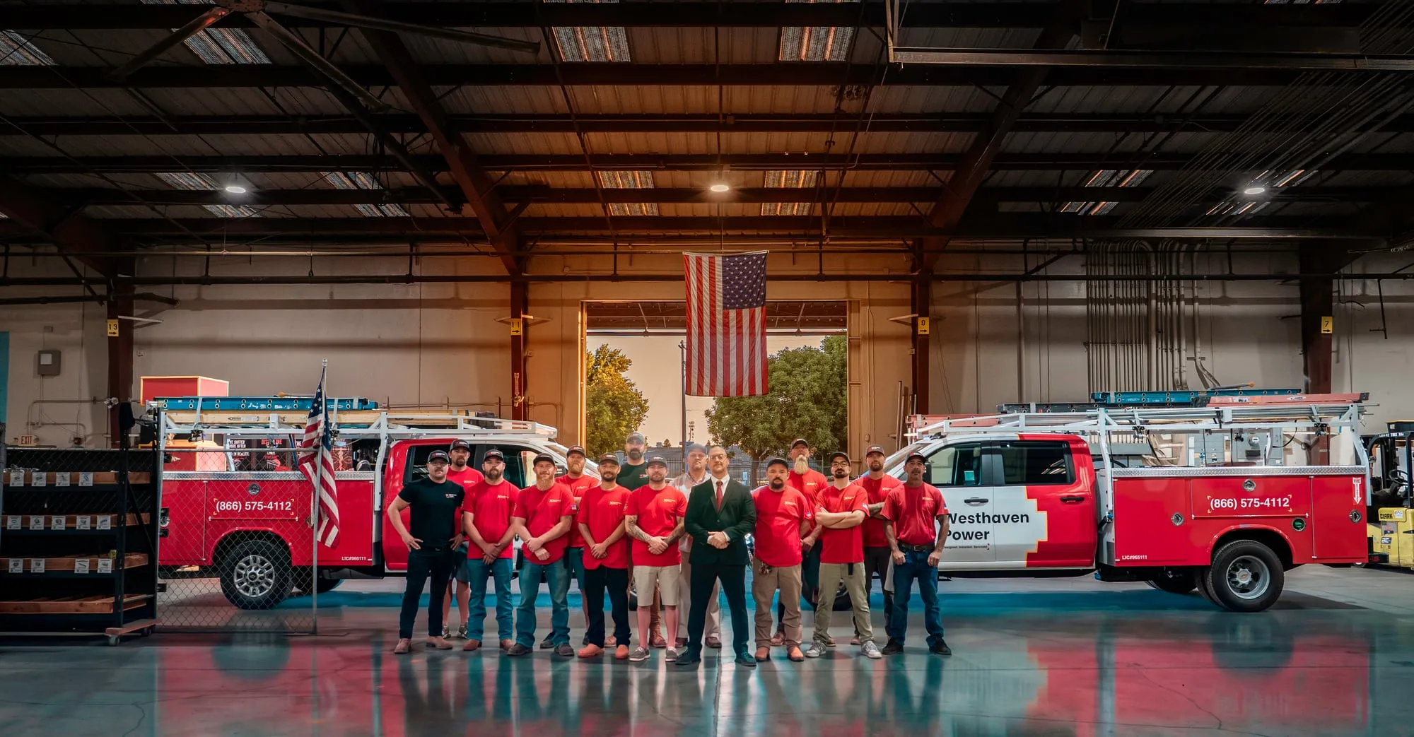 The Westhaven Power crew standing together in the Yuba City warehouse between two wrapped service trucks.